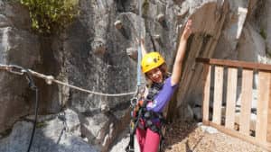 little girl with arms raised in the air happy after a successful rock climbing adventure at Quarry Park in Rocklin, CA