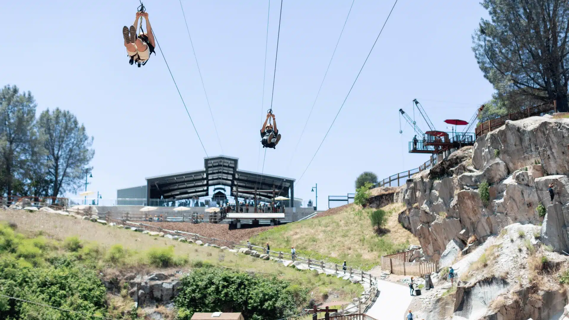 2 Adults zip-lining over rock canyon at Quarry Park Adventures.